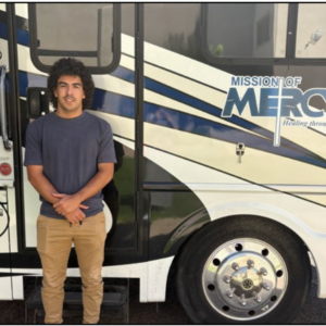 Max standing by MOM Bus with logo